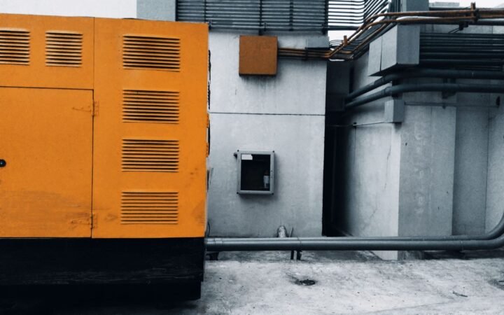 A large louvred standby generator enclosure on a pad outside a building
