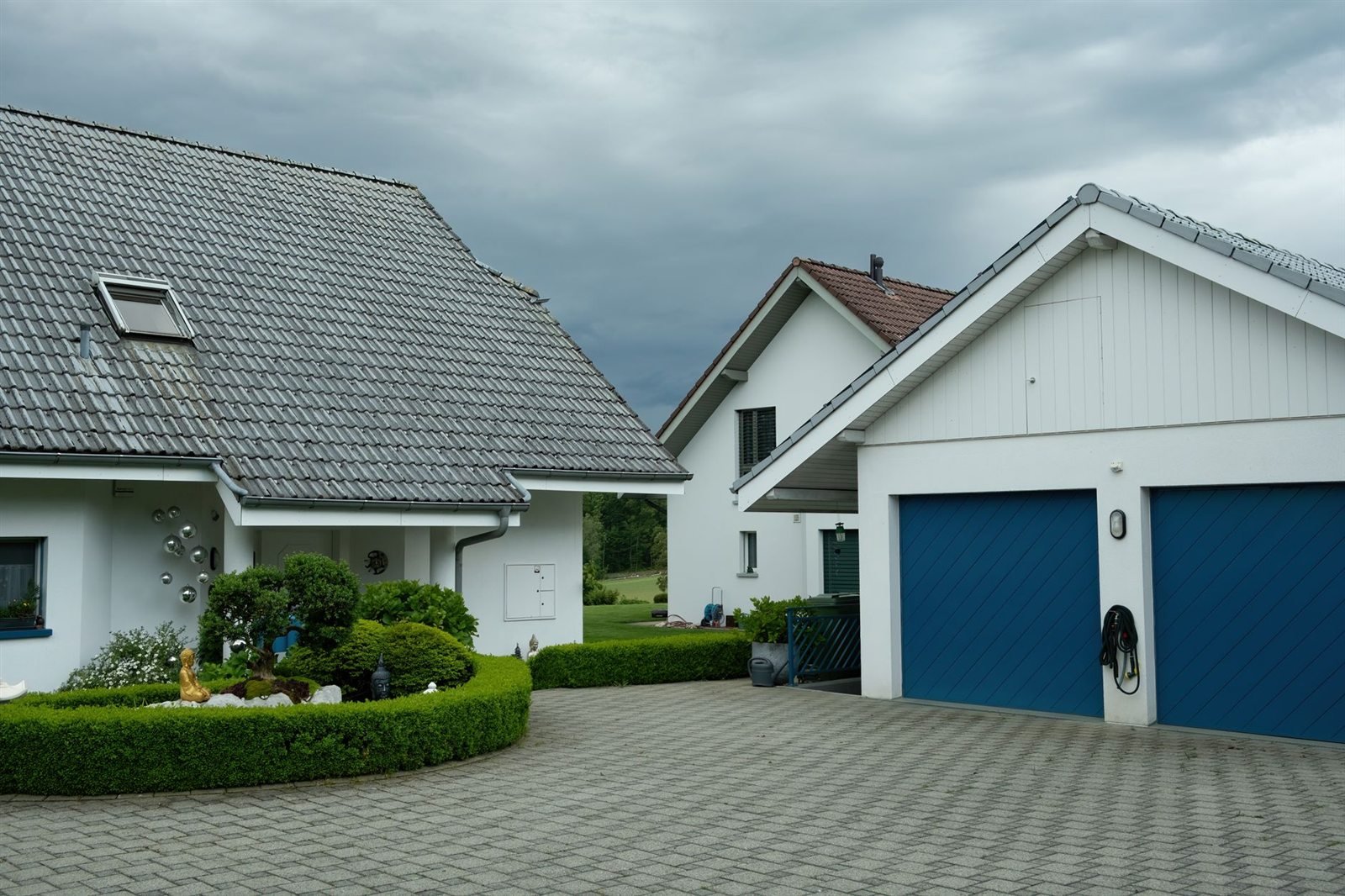 Houses with a driveway and garage under a dark, overcast storm sky