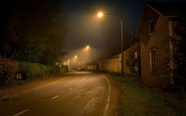 A dark residential street at night lit by a single streetlight
