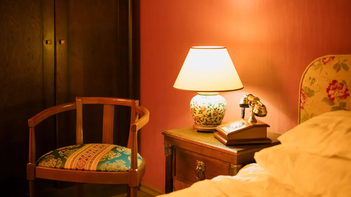 Bedside table lamp lit next to a bed