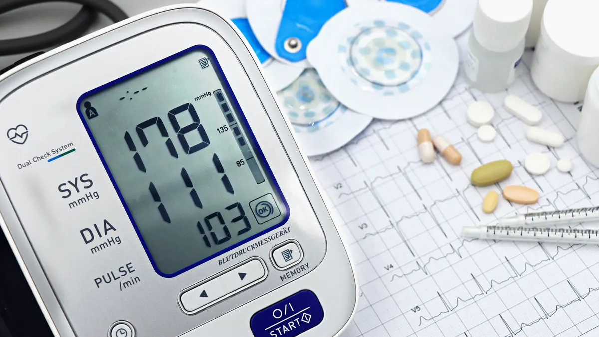Blood pressure monitor and pills on a medical chart