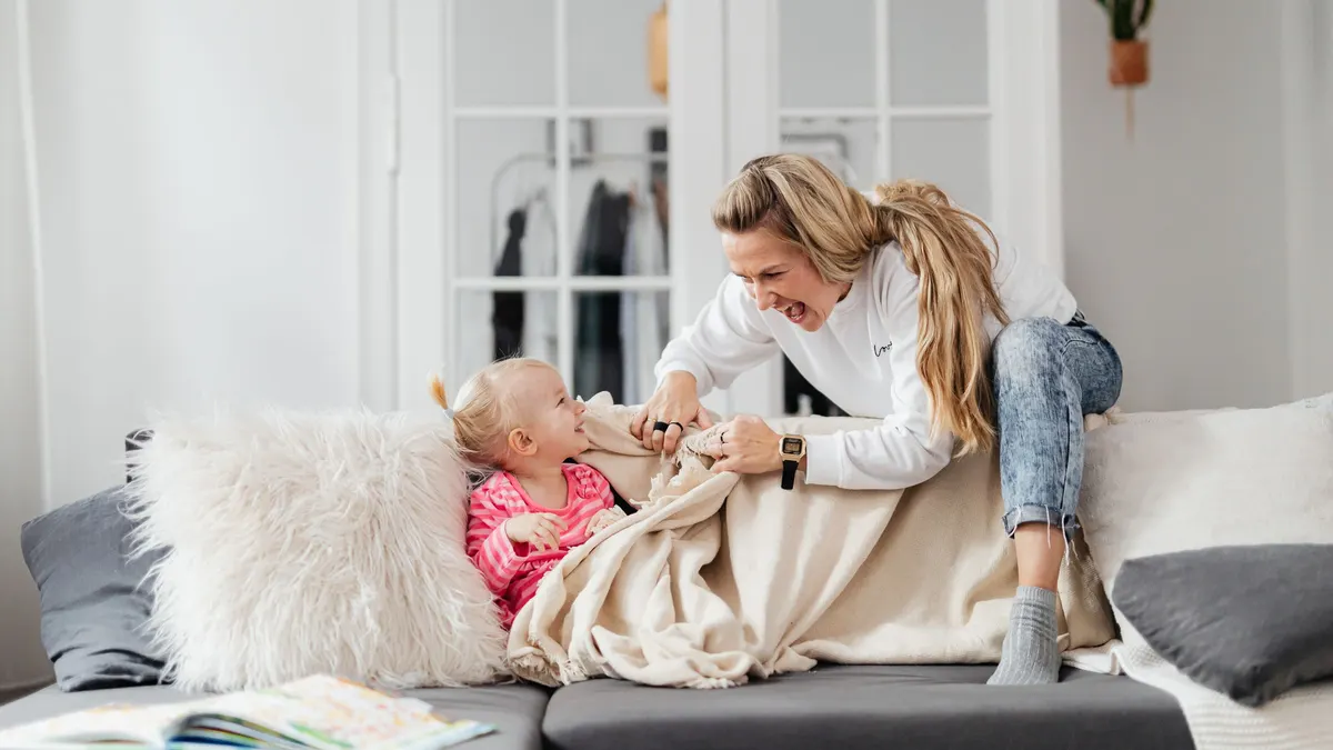 Mother and child wrapped in a blanket on a sofa