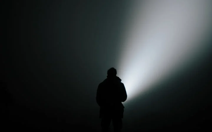 Person shining a flashlight beam in a dark room