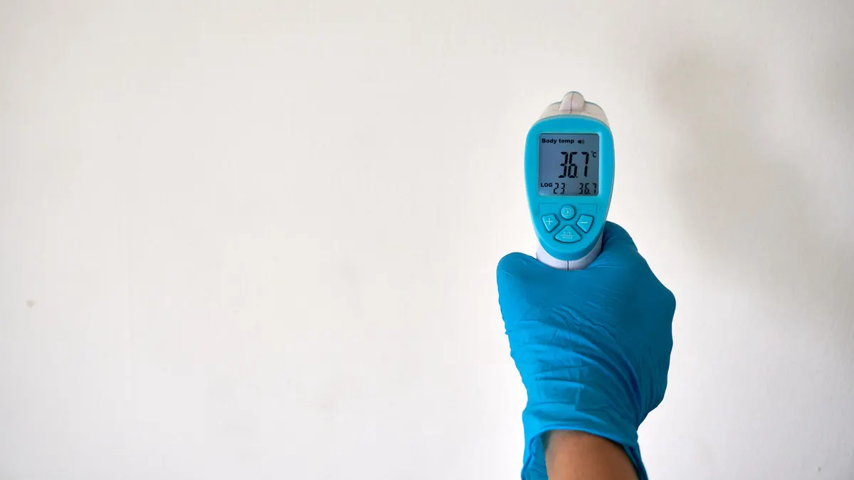 Infrared thermometer held against a white wall