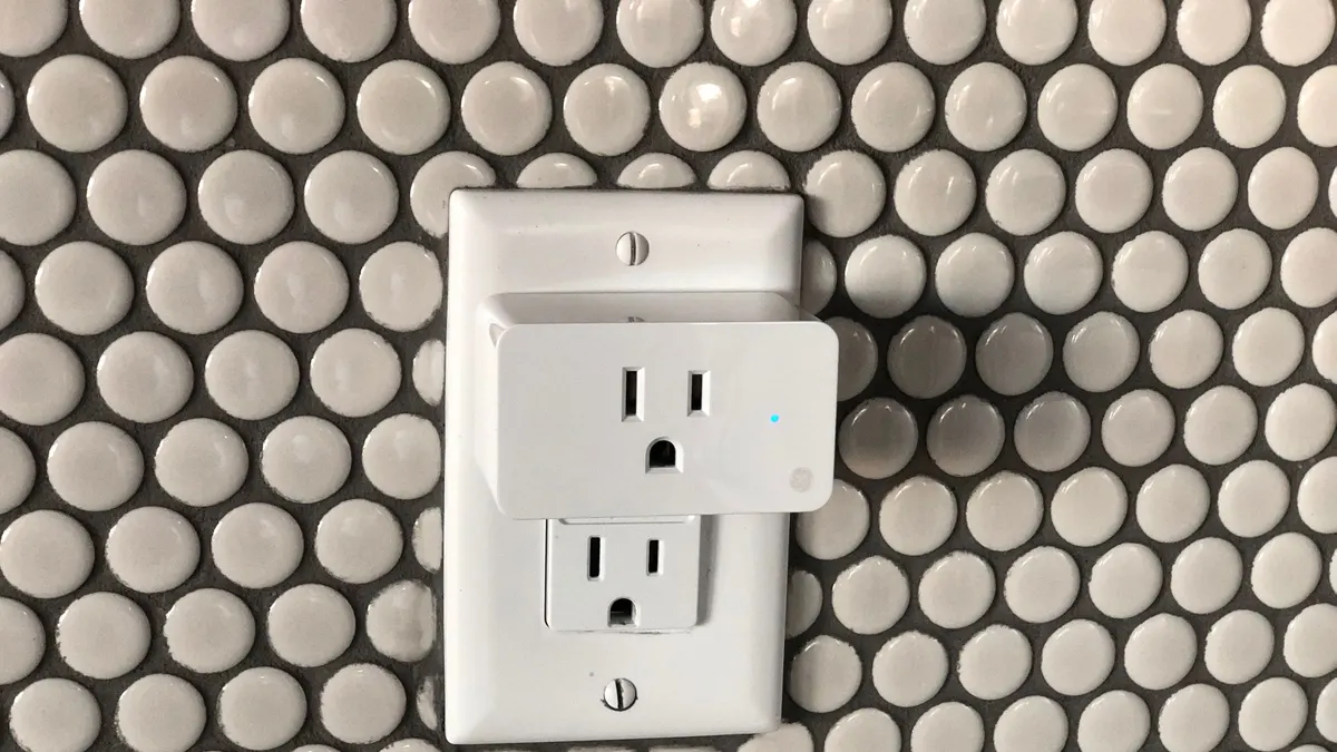 Smart plug in a wall socket on a tiled wall