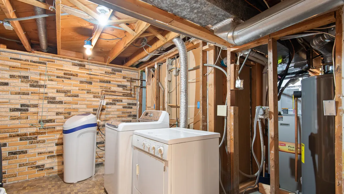 Unfinished basement utility area with a water softener and laundry appliances
