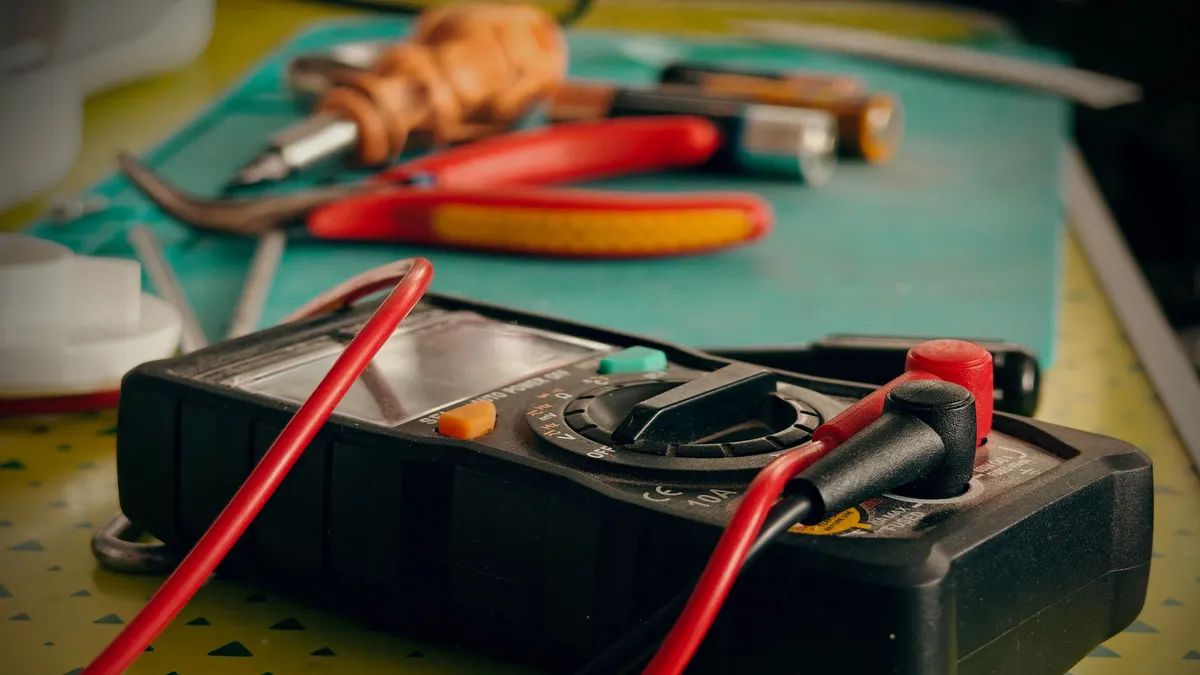 Digital multimeter with test leads on a workbench