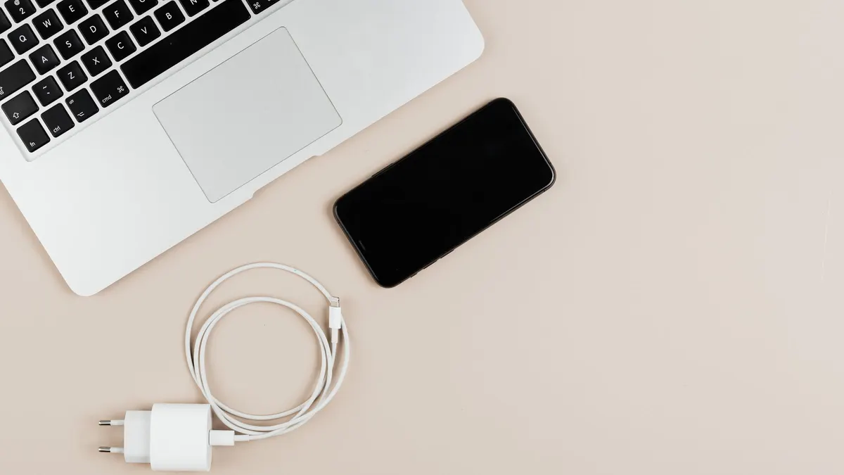 Laptop, smartphone and charger on a white desk