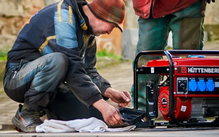 Two technicians working on a red portable generator outdoors