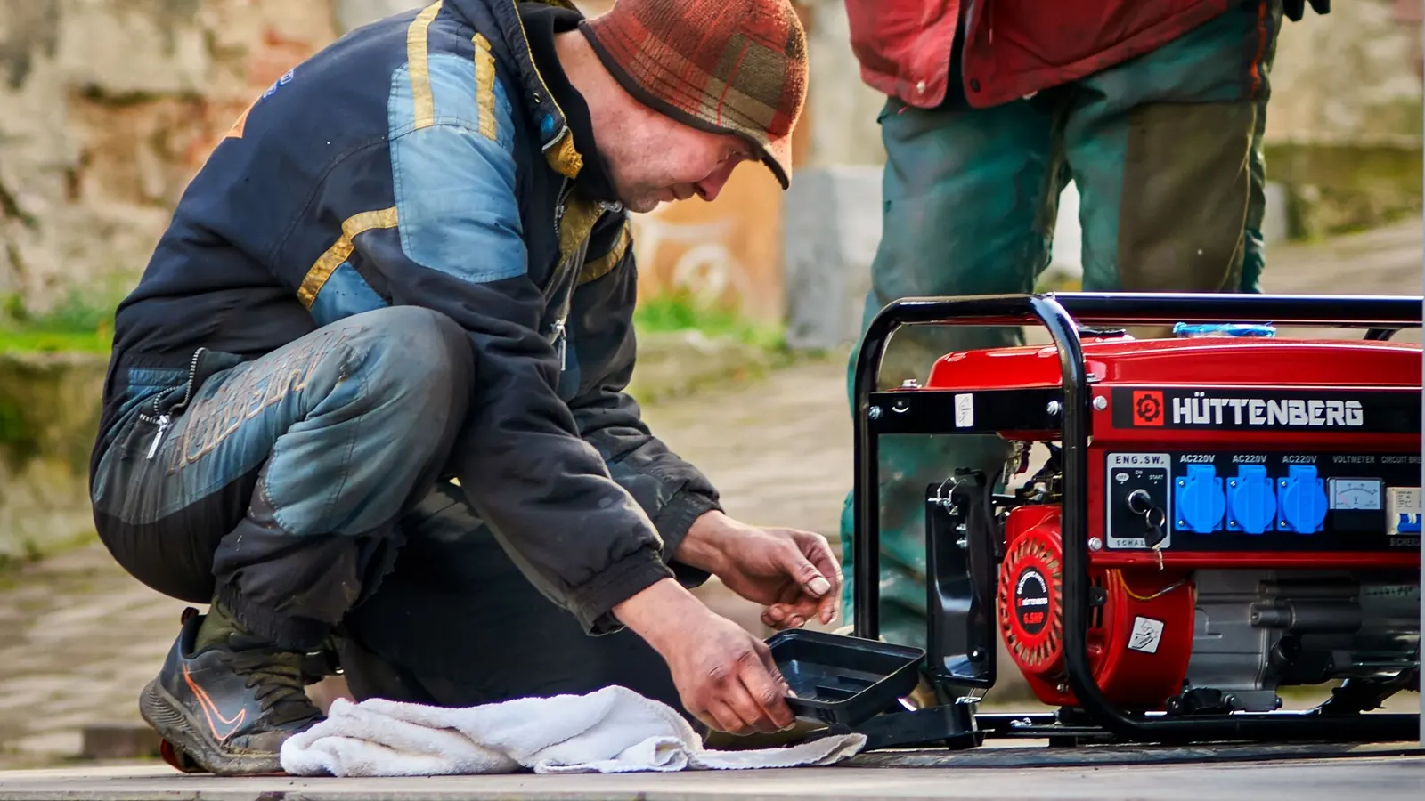 Two technicians working on a red portable generator outdoors