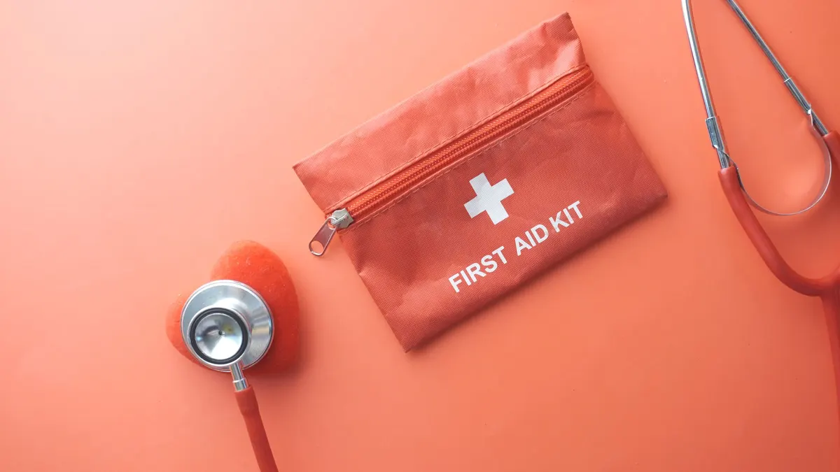 Red first aid kit and stethoscope on an orange background