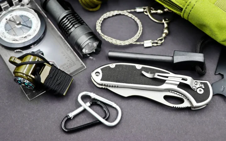 Flashlight, compass, knife and survival tools laid out on a table