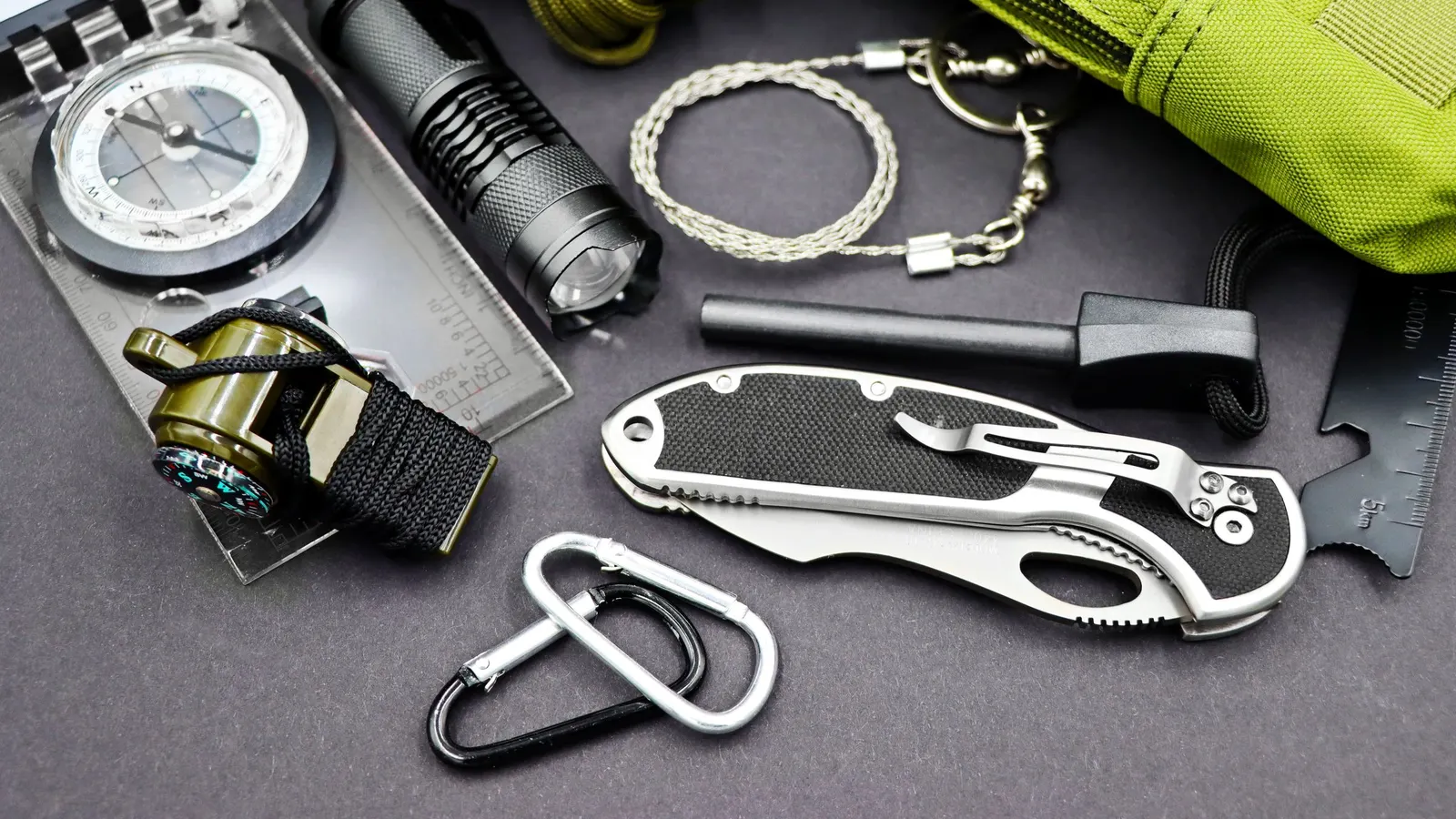 Flashlight, compass, knife and survival tools laid out on a table