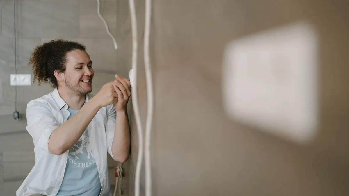 Electrician smiling while working on a wall outlet