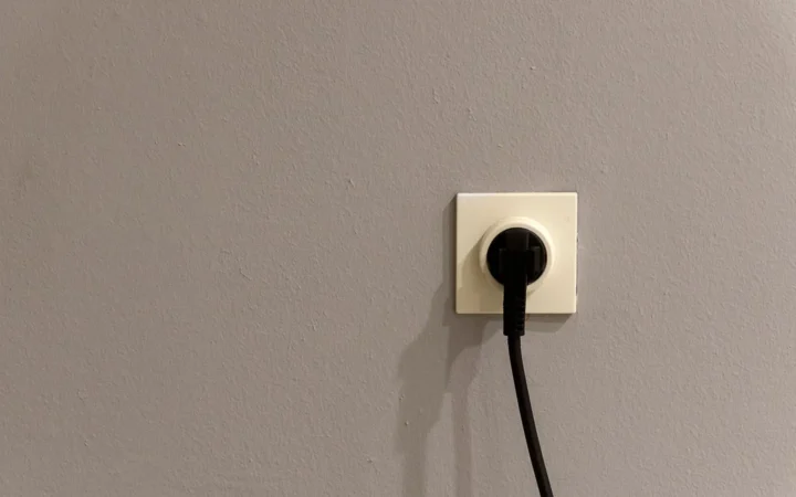 Black plug inserted into a white wall outlet