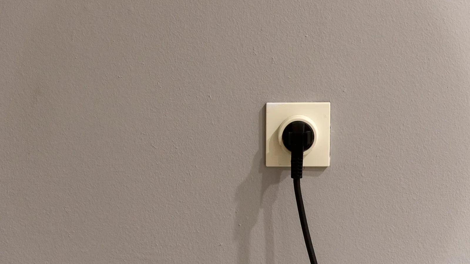 Black plug inserted into a white wall outlet
