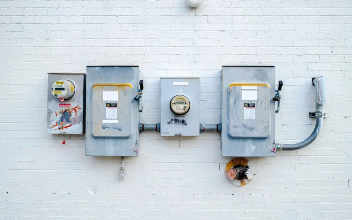 Electric meter and disconnect boxes on a white brick wall