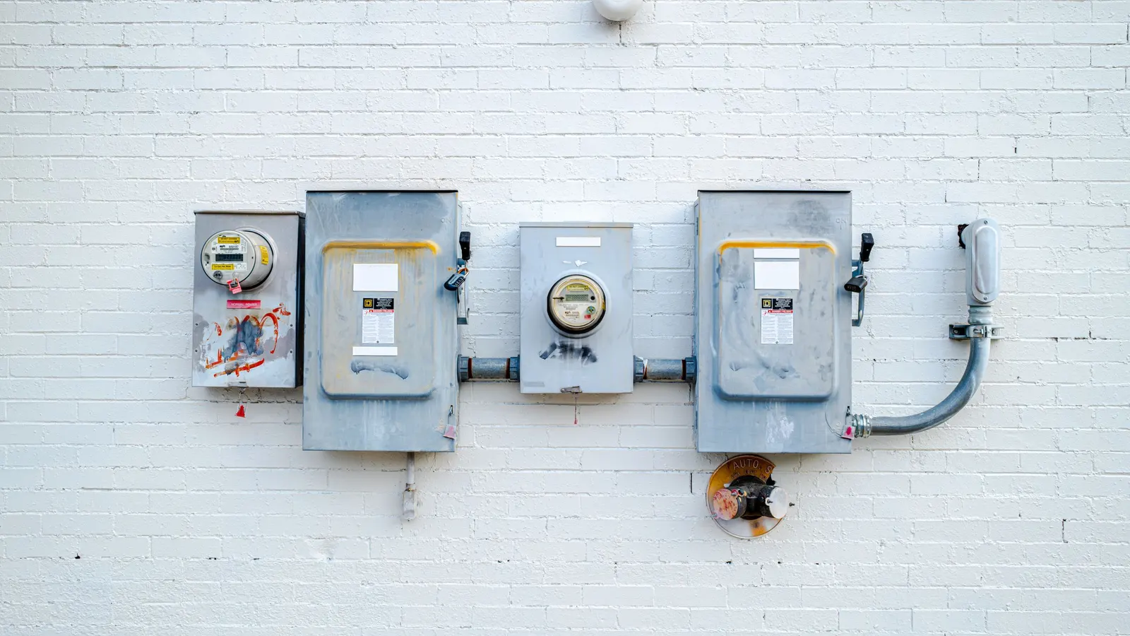 Electric meter and disconnect boxes on a white brick wall