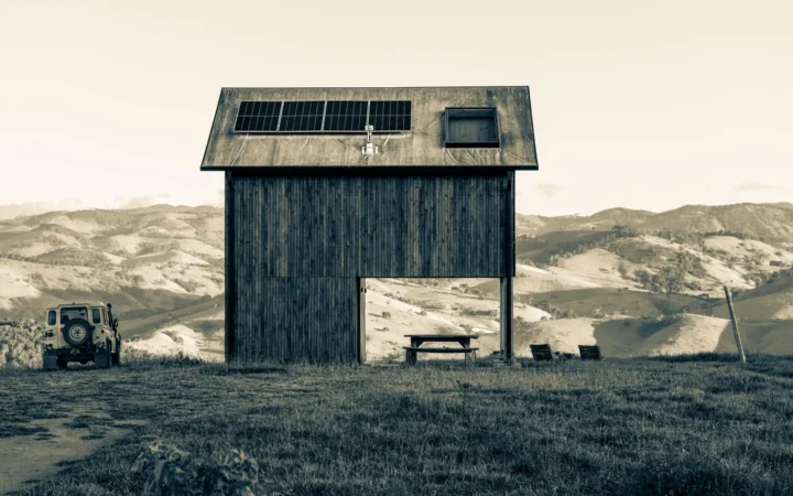Wooden cabin with solar panels on the roof in an open landscape