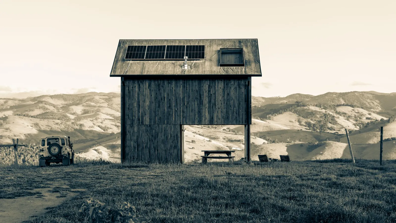 Wooden cabin with solar panels on the roof in an open landscape