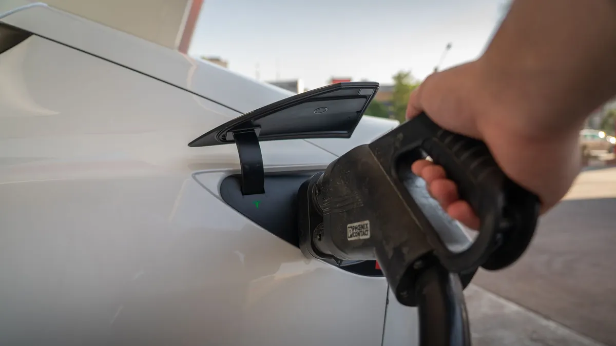 Hand holding an EV charging connector near a car's port