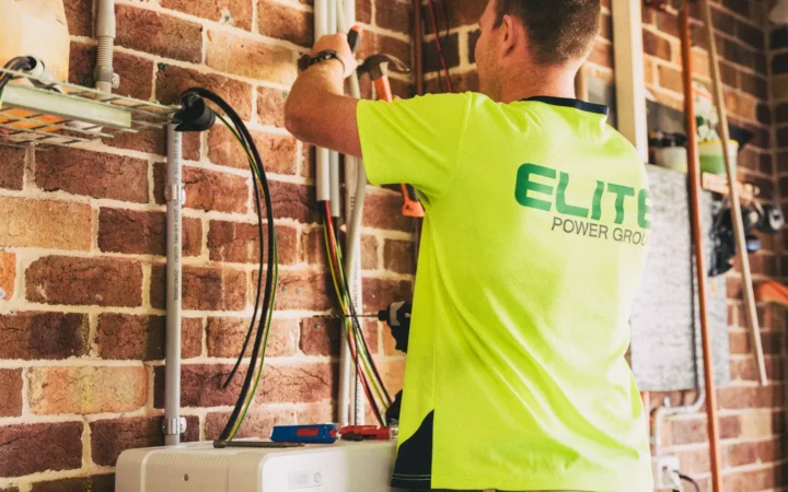 Installer wiring equipment for a home solar battery system on a brick wall