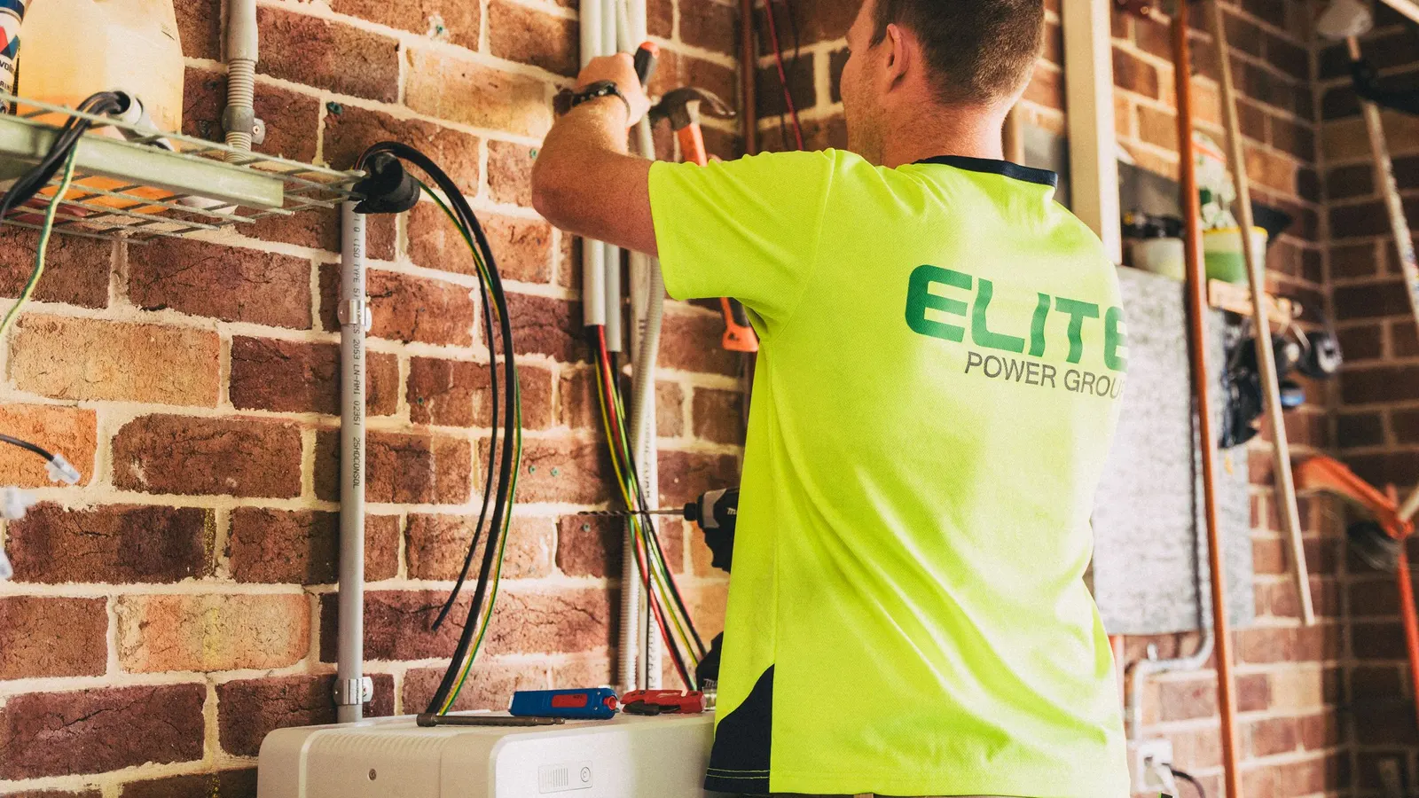 Installer wiring equipment for a home solar battery system on a brick wall