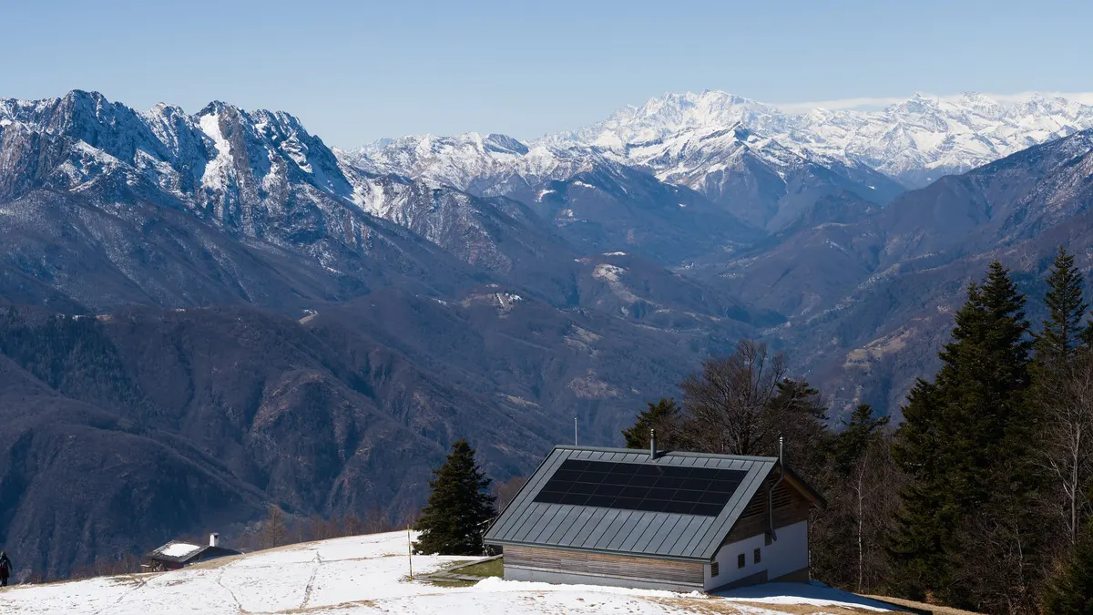 Roof solar panels below snow-covered mountains