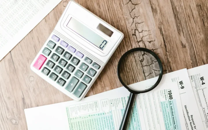 Tax forms with a calculator and magnifying glass
