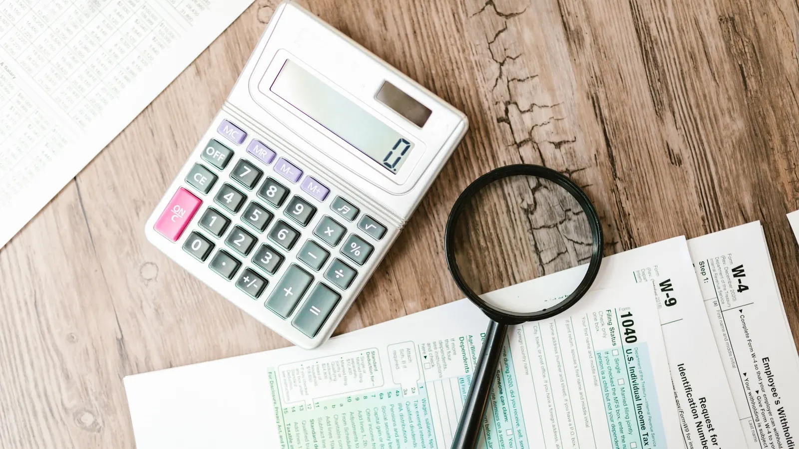 Tax forms with a calculator and magnifying glass