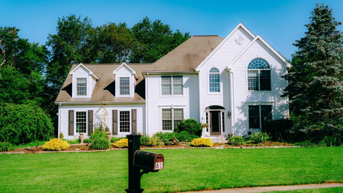 White two-story house with a green front lawn