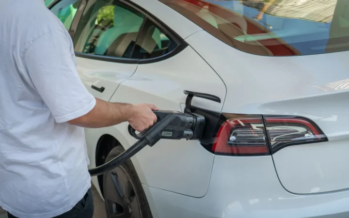 Man plugging a charging connector into a white electric car